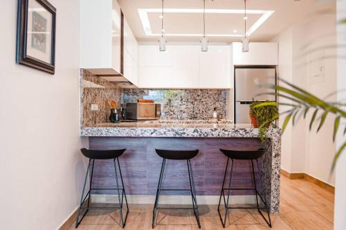 una cucina con bar con tre sgabelli di Luxury Apartment Toscana style, brand new a Guayaquil