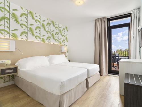 a bedroom with a large white bed and a window at H10 Suites Lanzarote Gardens in Costa Teguise