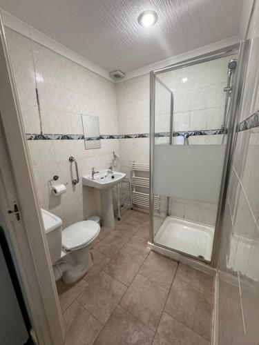 a bathroom with a shower and a toilet and a sink at All Seasons Gatwick Guest House & Parking in Horley