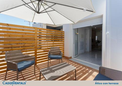 a patio with two chairs and a table and an umbrella at Apartamentos La BRUJULA by CadizRentals in Cádiz