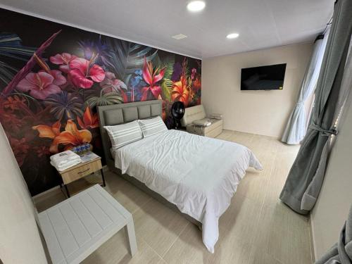 sypialnia z łóżkiem i ścianą kwiatową w obiekcie SIETE COLORES w mieście Chachagüí