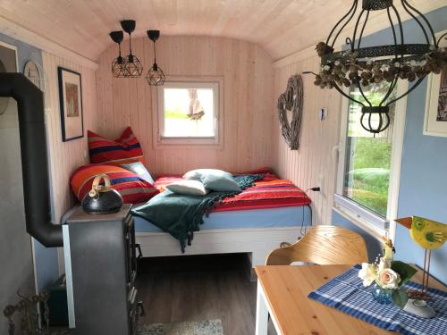 Habitación pequeña con cama y ventana en Schäferwagen im Auszeithof, en Niederfrohna