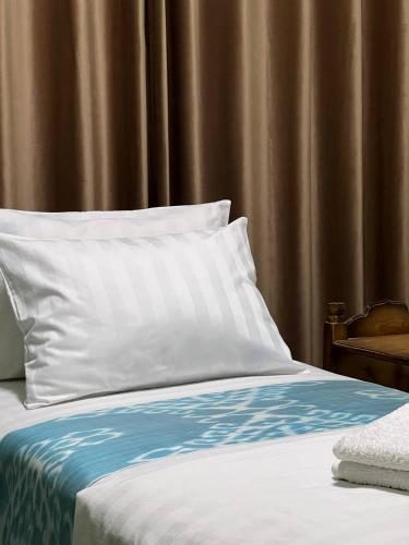 a bed with a white pillow and a brown curtain at 7 Pir in Bukhara