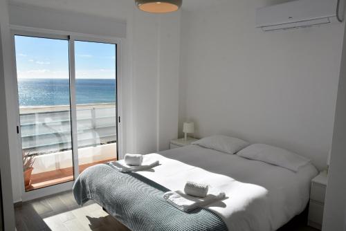 een slaapkamer met een bed en een groot raam bij Over the Beach in Monte Gordo