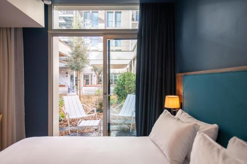 a bedroom with a bed and a large window at Hôtel de la Cité in Nantes