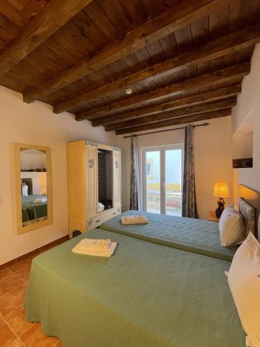 a bedroom with two beds and a large window at MONTE DAS AREIAS CASA DE CAMPO/PASSADIÇO/PATEO/RAMPA in Porches