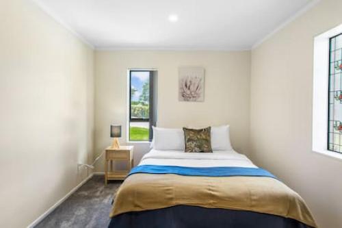 um quarto com uma cama e duas janelas em Meadowview Retreat is only 5 mins to beach em Waiau Pa