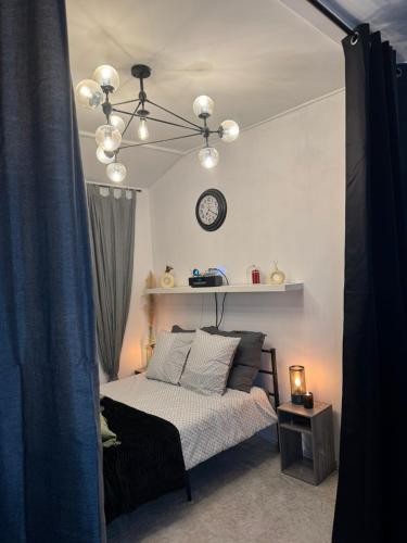 1 dormitorio con 1 cama y reloj en la pared en Maisonnette proche de Paris & Home cinema, en Bourg-la-Reine