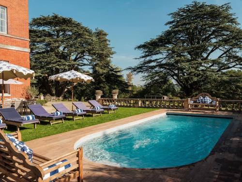 - une piscine avec des chaises et des parasols dans la cour dans l'établissement Wilde Cedar, à Binfield