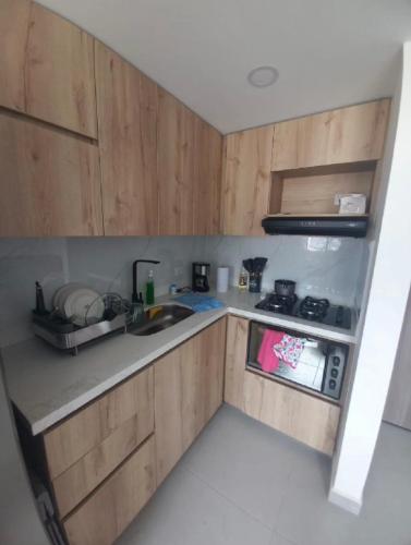 a kitchen with wooden cabinets and a sink at Apartamento en Edificio Puerto paraiso en Bello Antioquia in Bello