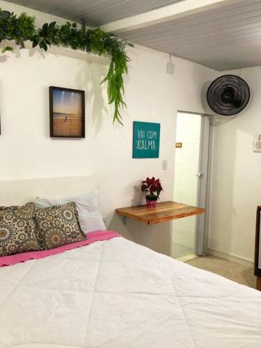 a bedroom with a white bed and a table at Suíte Colorida em Cabo Frio in Cabo Frio