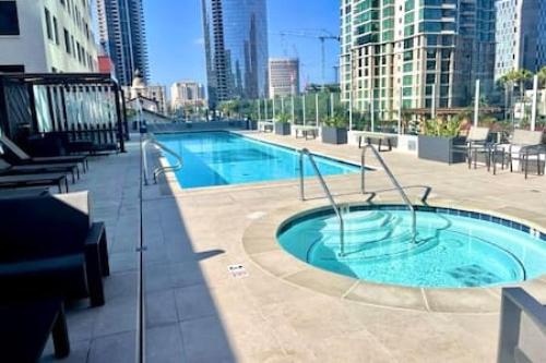a large swimming pool in a city with tall buildings at Luxe 1BR plus Den near Little Italy Gem in San Diego