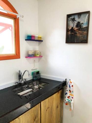 a kitchen with a black counter top and a sink at Suíte Colorida em Cabo Frio in Cabo Frio