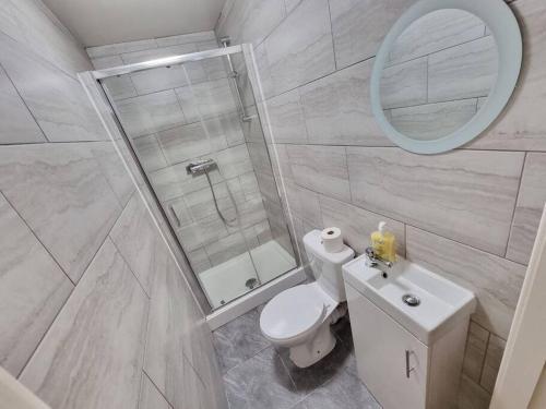 uma casa de banho com um WC e um chuveiro com um espelho. em Peaceful 4 Bedroom House with Free Parking em Liverpool
