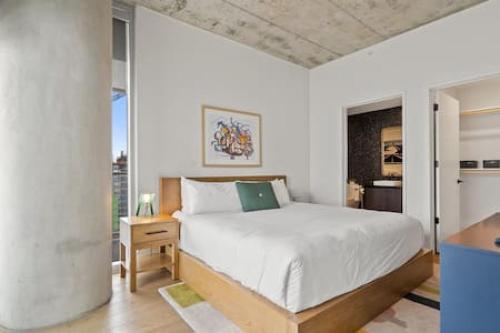 a bedroom with a white bed and a large window at 2BR Lux Highrise + Austin + Vibrant Rainey St in Austin