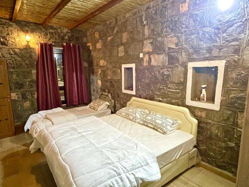 a bedroom with two beds and a stone wall at Jebel shams Sky in Misfāh