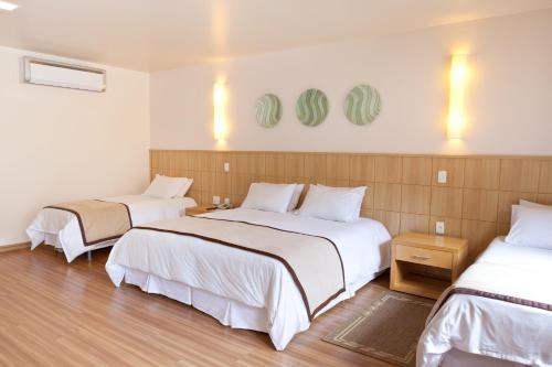 Habitación de hotel con 2 camas con sábanas blancas en Village Le Canton, en Teresópolis