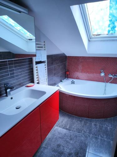 La salle de bains est pourvue d'une baignoire blanche et d'un mur en carrelage rouge. dans l'établissement Clotilde House, à Francavilla al Mare
