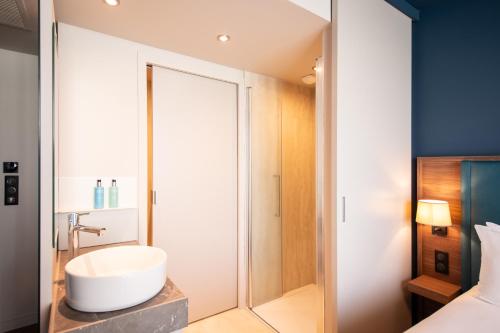 ein Bad mit einem Waschbecken und einer Dusche in der Unterkunft Hôtel de la Cité in Nantes