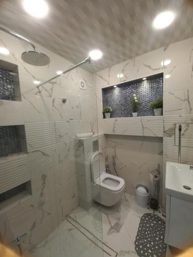 a white bathroom with a toilet and a sink at Apartment Krisiya in Burgas in Burgas City