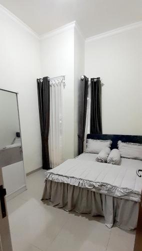 biała sypialnia z łóżkiem z poduszkami w obiekcie Villa Yanti F7 Permata Garden w mieście Karangploso