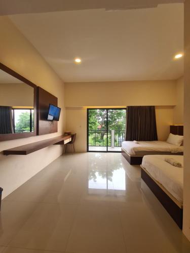 Merpati inn hotel في Dompu: غرفة نوم بسريرين ونافذة كبيرة