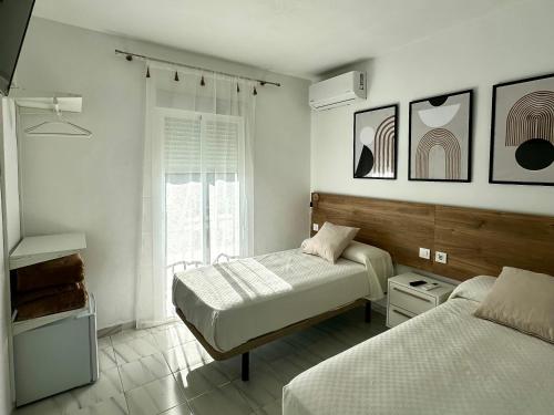 a bedroom with two beds and a window at Hostal Merino Jédula in Jedula