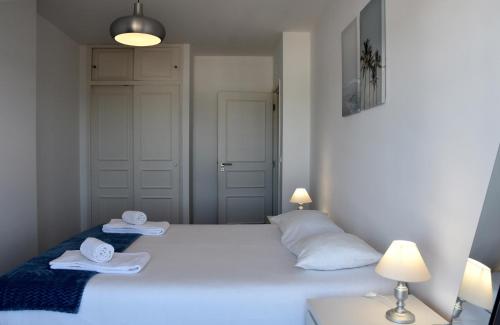 Un dormitorio con una cama blanca con toallas. en Beach House en Monte Gordo