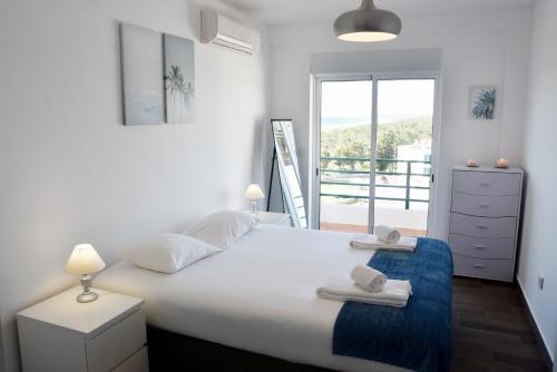 a bedroom with a large white bed and a balcony at Beach House in Monte Gordo