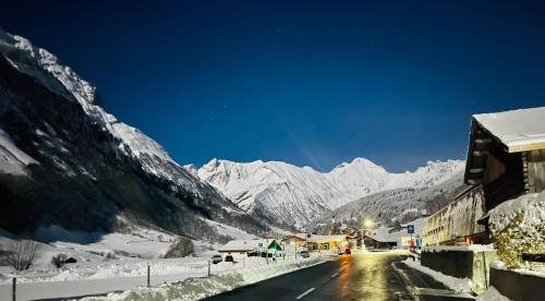a snowy street with snow covered mountains in the background at Sternen B&B & Italienisches Restaurant in Elm