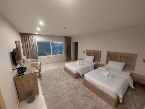 Cette chambre comprend deux lits et une télévision. dans l'établissement DouDou Pyramids View Hotel, au Caire