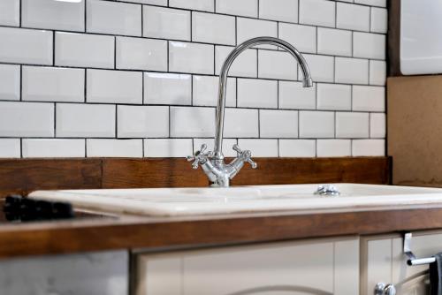 a sink in a kitchen with white tiled walls at Sally’s Cottage - Uttoxeter: Close to Alton Towers in Uttoxeter