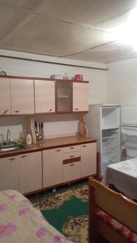 uma cozinha com armários brancos e uma cama num quarto em Жилой дом em Aralʼsk