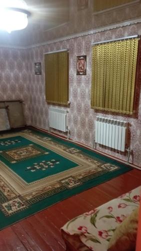um quarto com um tapete no chão e duas janelas em Жилой дом em Aralʼsk