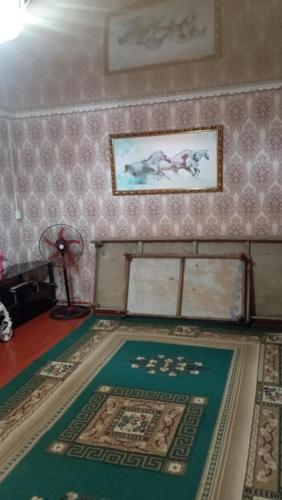 um quarto com um tapete e uma pintura na parede em Жилой дом em Aralʼsk