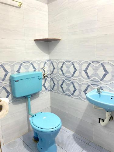 a bathroom with a blue toilet and a sink at PP White Town Rooms in Puducherry