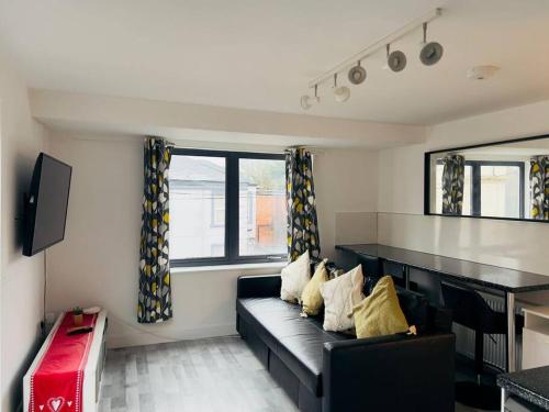 un soggiorno con divano nero e TV di Lovely 2 bedroom flat with free parking Flat 5 a Nottingham