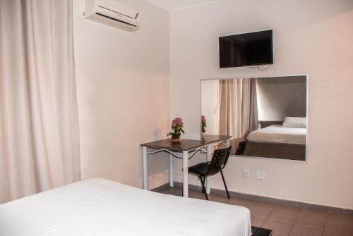 um quarto com uma secretária, uma cama e uma televisão em Hotel Viena em Taguatinga