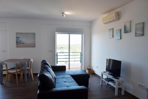 a living room with a black couch and a table at Beach House in Monte Gordo