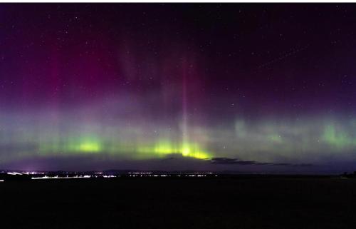 an aurora in the sky over a field at night at Uisge Beatha in Dornoch