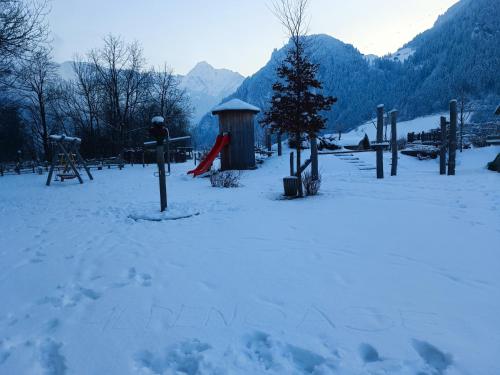 a snow covered park with a playground in the mountains at Alpenoase in Schwendau