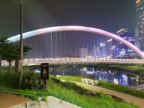 a lit up bridge over a river at night at Secret - 고층호수공원뷰,나만의영화관,미사역2분,120인치스크린,넷플,디즈니플러스,장기숙박추천 in Hanam