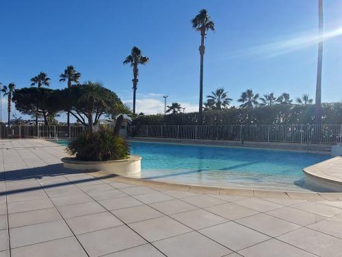 une piscine avec des palmiers dans un complexe hôtelier dans l'établissement CAP HERMES 2-3 pieces avec grande terrasse et apercu mer, à Fréjus