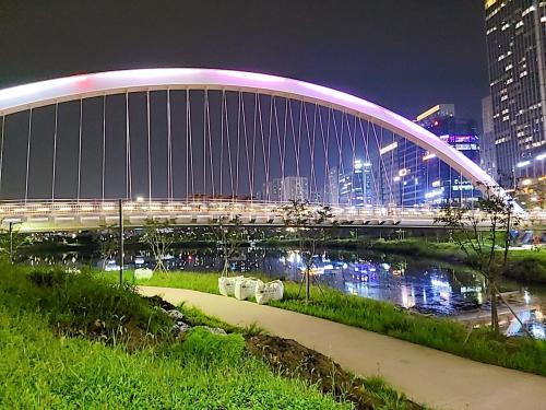 a bridge over a river in a city at night at Secret - 고층호수공원뷰,나만의영화관,미사역2분,120인치스크린,넷플,디즈니플러스,장기숙박추천 in Hanam