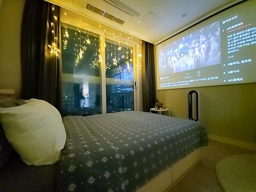 a bedroom with a bed and a large screen at Secret - 고층호수공원뷰,나만의영화관,미사역2분,120인치스크린,넷플,디즈니플러스,장기숙박추천 in Hanam