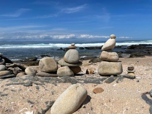 a stack of rocks on a beach near the ocean at Aloe Studio in Jeffreys Bay