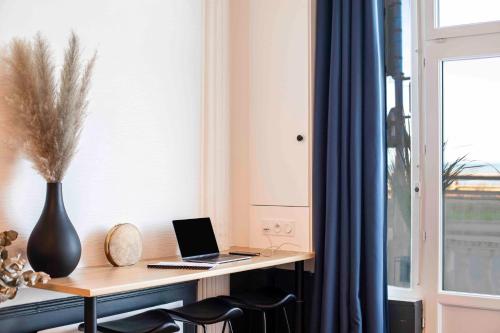 a desk with a laptop on it next to a window at WELC'HOME IN HOULGATE - Vue et accès direct sur mer in Houlgate