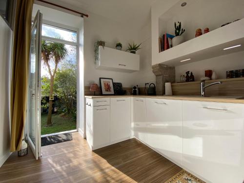 een keuken met witte kasten en een groot raam bij Studio au pied du phare Vue Mer in Roscoff