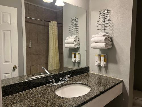 W łazience znajduje się umywalka, lustro i ręczniki. w obiekcie Hometown Inn North Hills w mieście North Hills