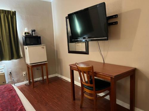 a room with a desk and a television on the wall at Hometown Inn North Hills in North Hills